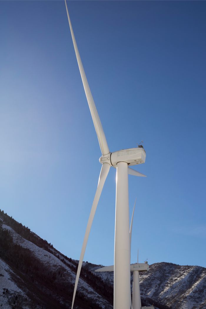 Majestic wind turbines in Utah mountains symbolizing clean renewable energy against a clear sky.